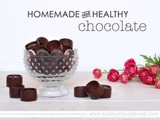 chocolate candies in a glass bowl on a table with pink flowers and the words homemade healthy chocolate