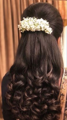 the back of a woman's head with long hair and flowers in her hair