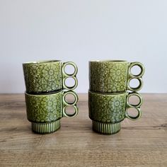 four green cups sitting on top of a wooden table