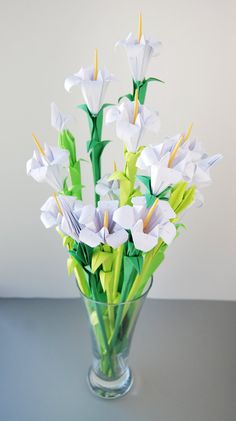 a glass vase filled with white flowers on top of a gray table next to a wall