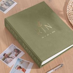 a green book with gold lettering on it next to photos and a pen, along with other personalized items