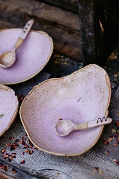 three bowls with spoons in them sitting on a wooden table next to some dried herbs