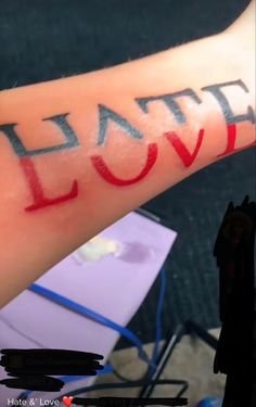 the word love is written on someone's arm with red ink and black lettering