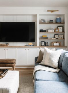 a living room filled with furniture and a flat screen tv mounted on the wall above it