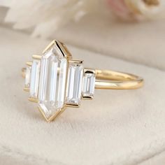 an engagement ring with three baguettes on the side, and a flower in the background