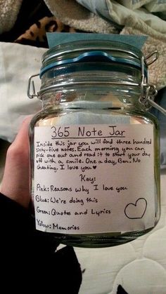 a person holding up a jar with writing on the lid and paper attached to it