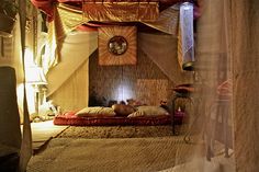 a room with a bed, lamps and pictures on the wall above it that is decorated in gold and red