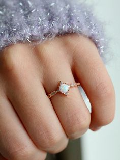 a woman's hand wearing a ring with an opal in the middle and diamonds on it