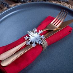 two forks and a knife on a blue plate with red napkins that have snowflakes on them