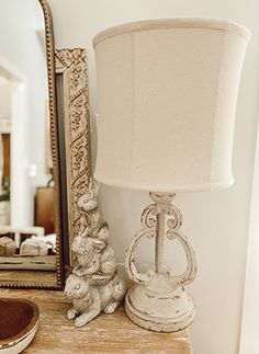 a white lamp sitting on top of a wooden table next to a mirror and a dog figurine