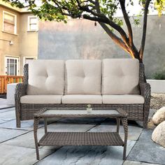 a couch sitting on top of a stone floor next to a tree