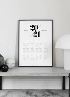 a black and white calendar print on a table next to a lamp, vases and other items