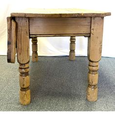 an old wooden table with two legs and a drawer on the top, sitting on carpeted floor