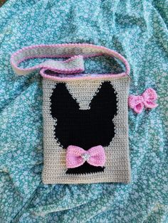 a crocheted bag with a pink bow on the handle and a black face