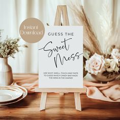 a wooden easel with a sign that says guess the sweet mess on it next to some flowers