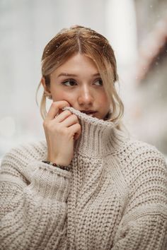 a woman in a white sweater is holding her hand to her mouth