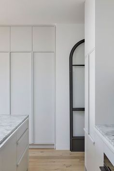 an empty kitchen with white cabinets and marble counter tops, along with wood flooring