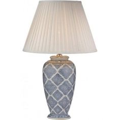 a blue and white lamp with a beige shade on the top, sitting next to a white lampshade