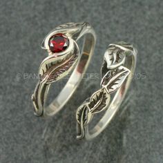 two rings with leaves and a red stone in the middle, sitting on a gray surface