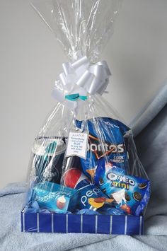 a blue gift bag filled with candy and candies sitting on top of a bed