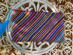 a colorful purse sitting on top of a white table next to a blue tassel