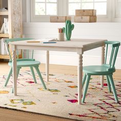 two children's chairs at a table with a rug on the floor and bookshelf in the background