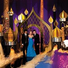 a couple standing in front of a purple and gold wedding cake at a reception venue