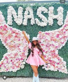 a woman standing in front of a flower wall