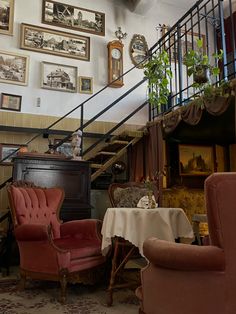 a living room filled with furniture and pictures on the wall above it's stairs