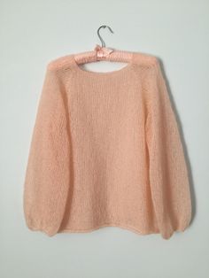 a pink sweater hanging on a hanger