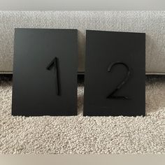 two black square numbers sitting next to each other on a carpeted floor in front of a couch