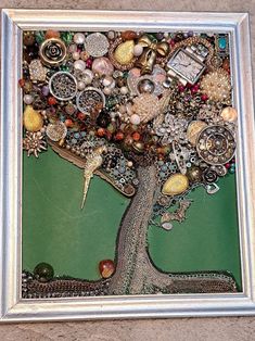 a tree with lots of beads and other things on it's branches in a silver frame