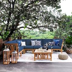 an outdoor living area with blue couches and wooden tables