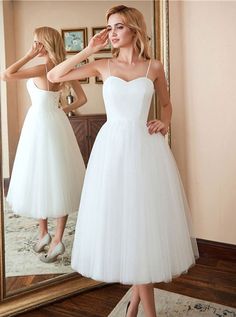 a woman standing in front of a mirror wearing a white dress