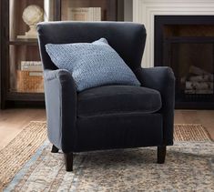 a blue chair sitting on top of a rug in front of a fireplace