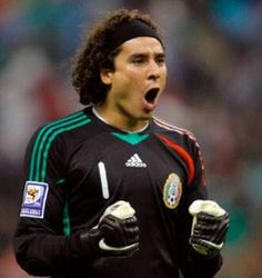 a soccer player with his mouth open and gloves in front of him, making a funny face