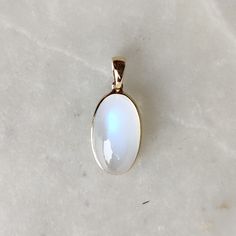 ITEM DESCRIPTION: >>The pendant is made from Solid 14K Yellow Gold. Gemstone used is absolutely natural and ethically sourced. >>Natural Rainbow Moonstone with a beautiful blue sheen in Oval shape, cabachon and bezel setting is studded on it with utmost precision. >>This is a minimalist design and is absolutely hassle-free and everyday jewelry. Gem: Rainbow Moonstone Gem size: 10x18 mm Gem weight: 11.94 carats Gold purity: 14K (58.33% approx.) Gold weight: 0.57 grams Gross weight: 2.96 grams The White Oval Cabochon Jewelry With Large Stone, Celestial White Jewelry With Birthstone, White Moonstone Jewelry Oval Cabochon, White Oval Cabochon Birthstone Jewelry, Celestial White Gemstone Jewelry, White Moonstone Gemstones For Gift, White Moonstone Gemstones As Gift, White Gemstone Oval Pendant Jewelry, White Moonstone 14k Gold Ring Gift