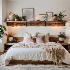 a bed with pillows and blankets on top of it in a room filled with potted plants