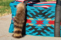 a cat tail is sticking out of the inside of a blue and red handbag