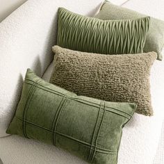 three green pillows sitting on top of a white couch