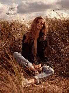 a woman sitting on the ground in tall grass