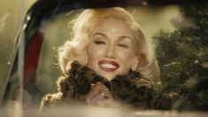 a woman in a fur coat looking out the back window of a car with her hand up to her face