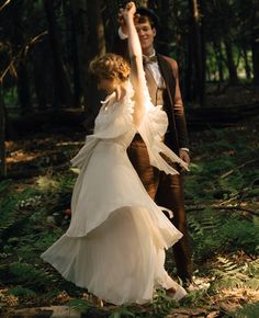 a man and woman are dancing in the woods