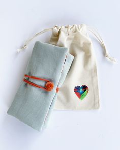 Designed for those who appreciate handmade gifts and colorful objects, this linen jewelry roll pouch ensures the protection of your precious jewelry during your adventures.  The interior pockets are designed for optimal organization, ensuring that every piece is held securely in place. When not in use, simply roll up the pouch and close it with a cotton cord and button. Made from a combination of almond green linen and cotton fabric featuring a charming tropical pattern, the pouch's interior is lined with a plain green cotton fabric. The large linen jewelry roll pouch features specialized pockets: A deep flapped pocket with 5 tapes and snap buttons for organizing necklaces, complete with a mesh part for easy visibility. A zipped pocket dedicated to storing bracelets securely. An earring or Jewelry Roll Travel, Tropical Gifts, Travel Bag Essentials, Travel Jewelry Organizer, Tropical Fabric, Earring Storage, Jewelry Roll, Necklace Organizer, Large Jewelry