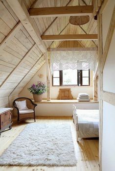 an attic bedroom with wood floors and white walls, along with a large rug on the floor