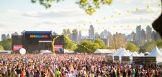 a large group of people standing in front of a stage at an outdoor music festival