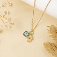 Esme Protect yourself in style with the Evil Eye & Hamsa Charm Necklace. This unique necklace features two protective charms: a sparkling blue sapphire Evil Eye and a diamond-studded Hamsa, both on a dainty solid gold chain. This beautiful piece wards off negativity and brings good luck, adding elegance to any outfit. Layer with other necklaces for a personalized look. - Handmade- Solid Gold- Natural Diamonds and Blue Sapphires- G Color, SI Quality Diamonds- Dimension: 7 mm- Total Diamond Carat Dainty Sapphire Jewelry With Diamond Accents, Diamond Charm Necklace As Gift, Diamond Charm Necklace For Gift, Fine Jewelry Evil Eye Pendant, Luxury Charm Necklaces With Diamond Accents For Gift, Luxury Charm Necklace With Diamond Accents For Gifts, Sapphire Jewelry With Diamond Accents As Gift, Blue Tarnish-resistant Jewelry For Anniversary, Diamond Evil Eye Jewelry Gift