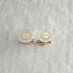 two gold cufflinks with an emblem on them