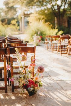 a bunch of wooden chairs with flowers in them on the ground next to each other