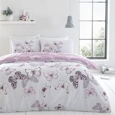 a white bed with pink and purple butterflies on the comforter, along with two pillows